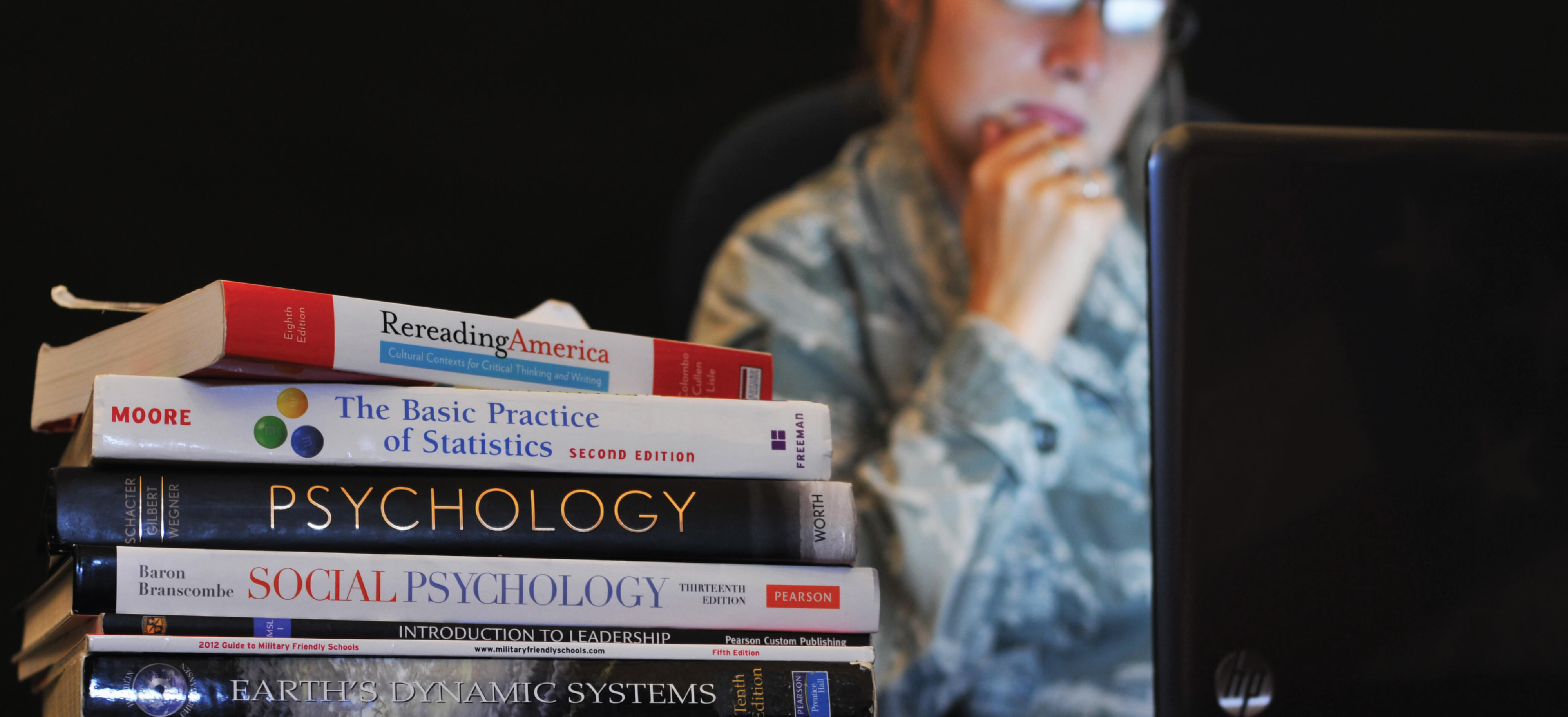 Airman works on computer with textbooks nearby