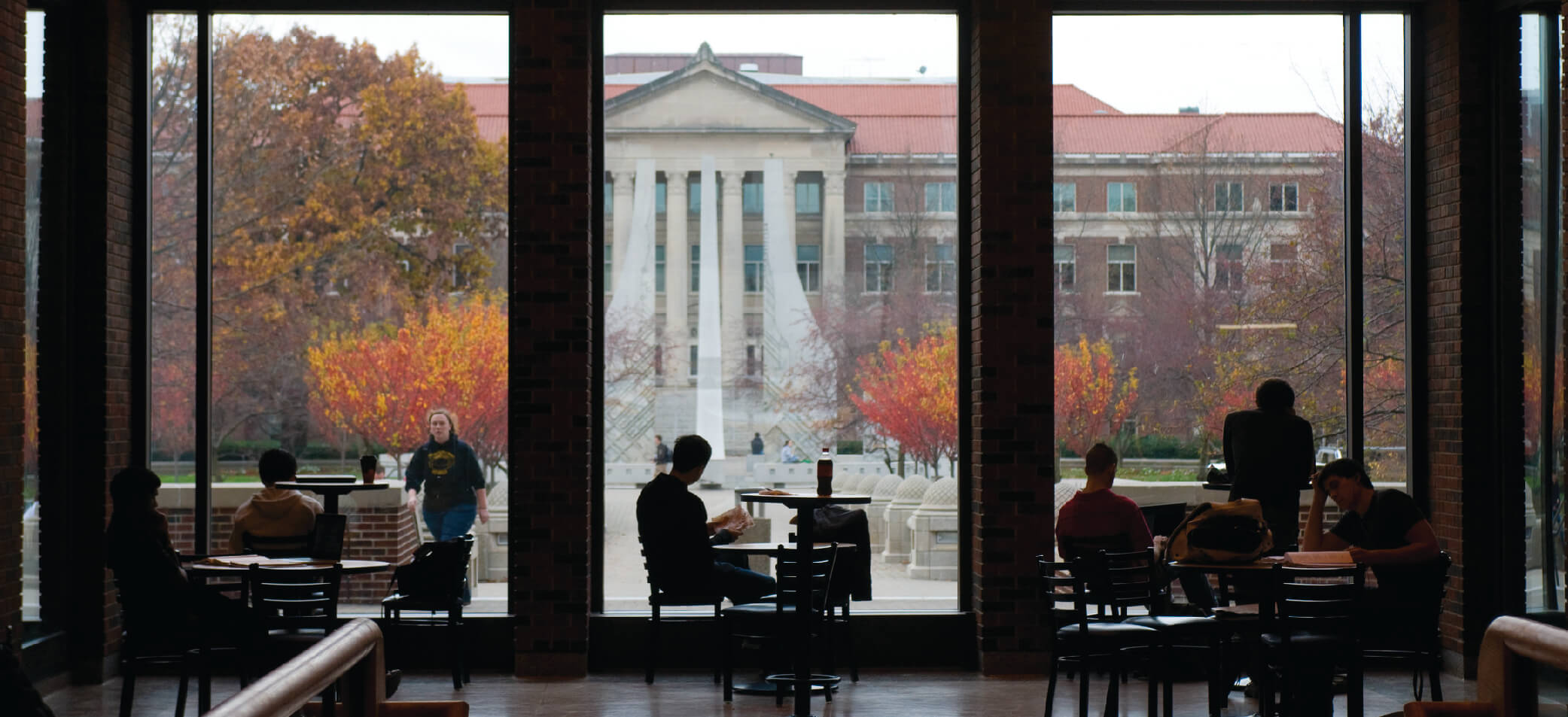 Students study with a window showing Purdue's campus behind them