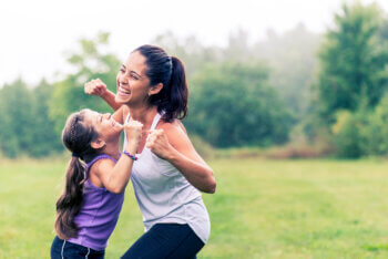 Mom and daughter flexing in green park